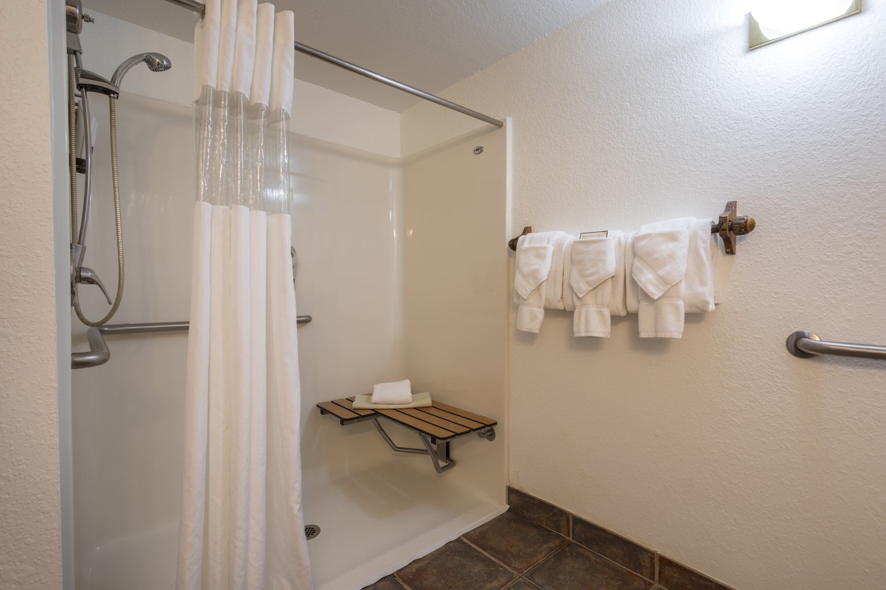 white bathroom with rock in shower and white towels 
