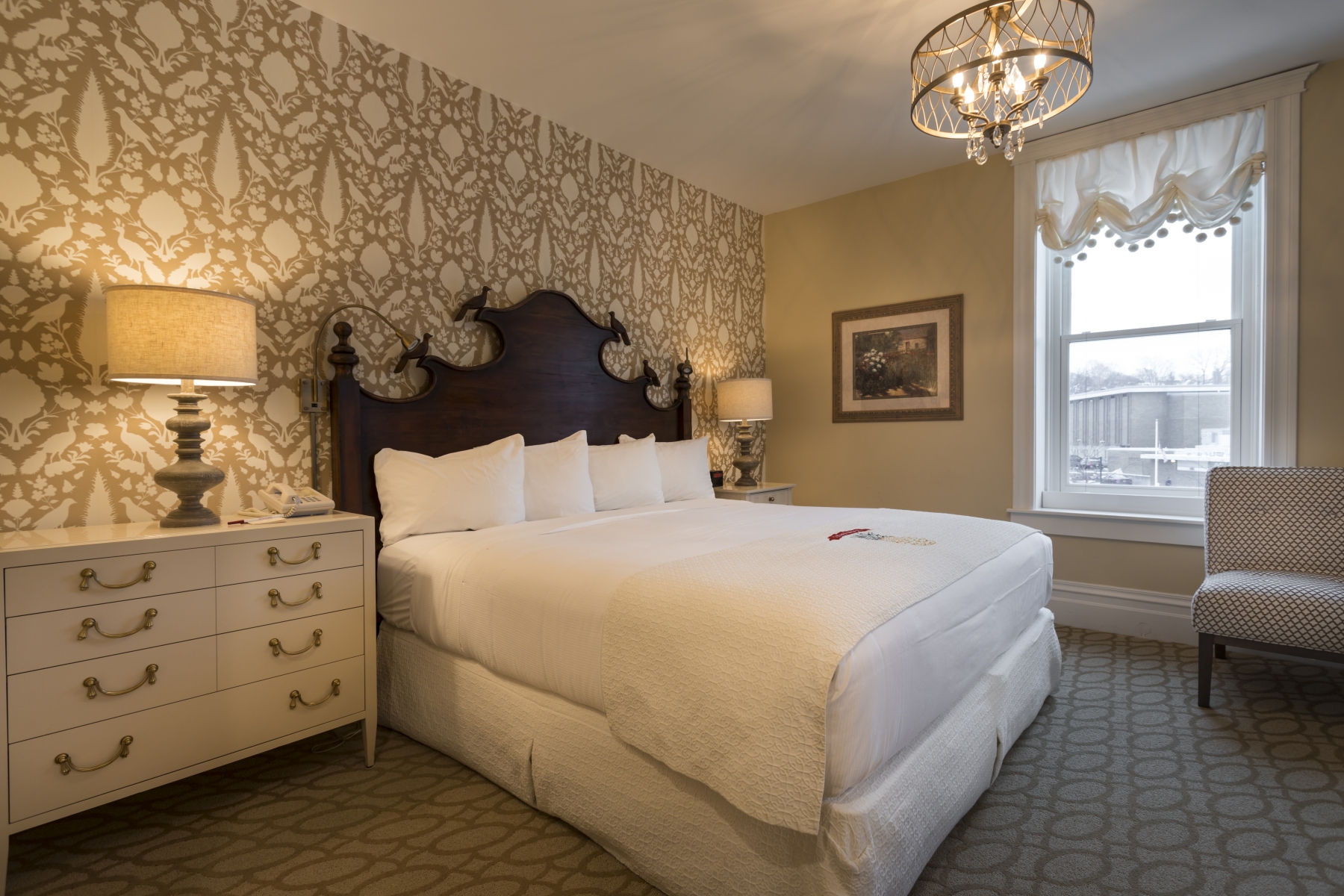 hotel room with white sheets and pattered tan wallpaper 