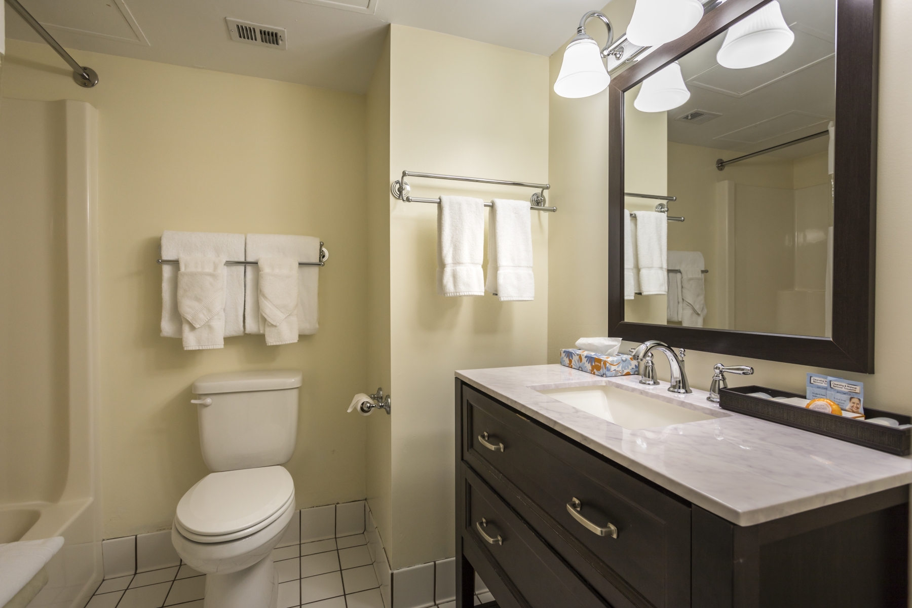 bathroom with large mirror, yellow walls, and white towels hanging on the wall