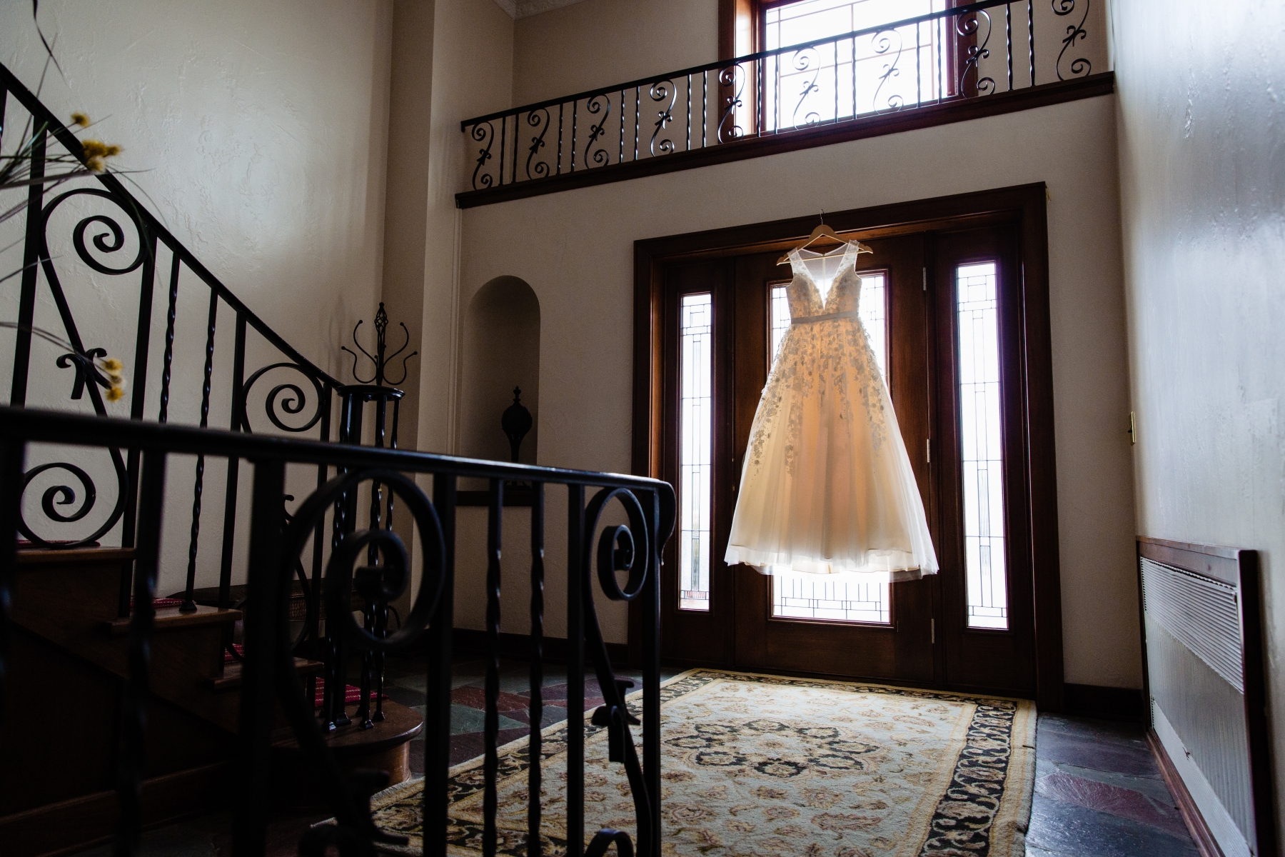 wedding dress hanging on the door in the hotel lobby with the light shining through