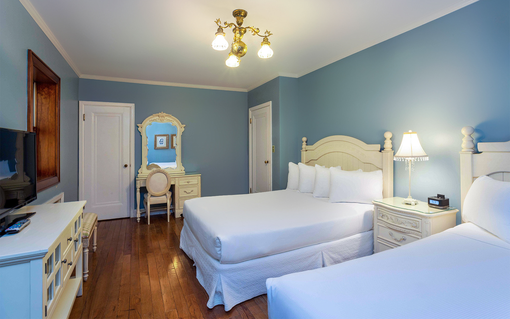 blue bedroom with two double beds and a mirror