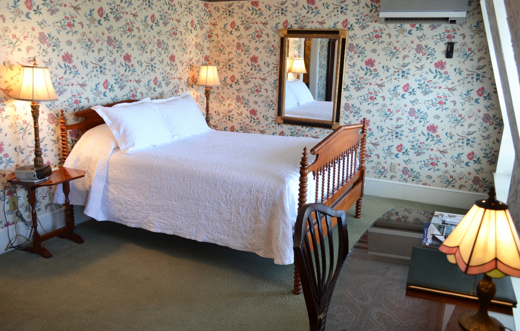 Hotel room with floral wallpaper and 1 bed with white sheets 