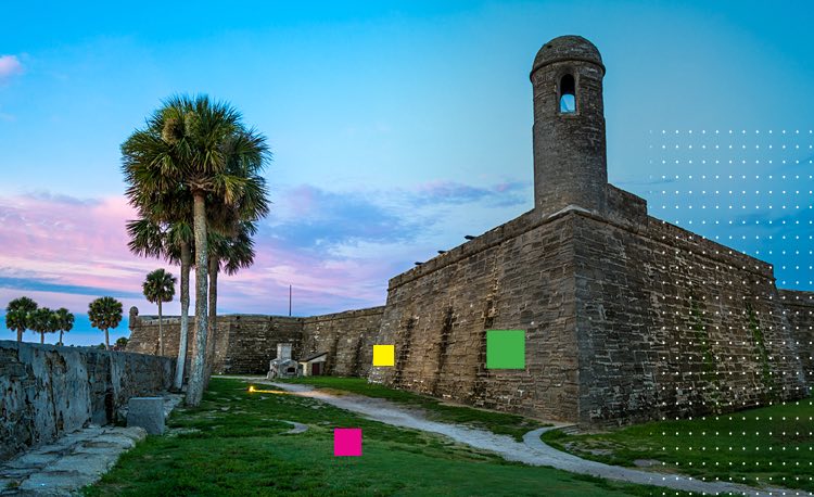 Ancient ruin building surrounded by palm trees by the water