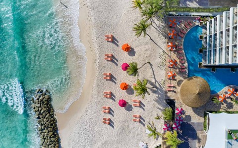 ariel view of beach and lounge chairs with orange and pink umbrella