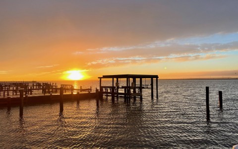 sunset over the water with a dock in view 