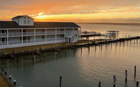 exterior of anchor inn with a dock and water with the sunset in the background