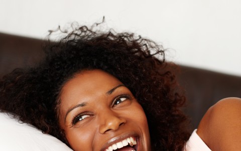 woman laughing and laying on a pillow