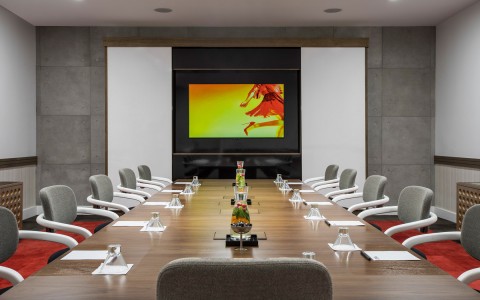 long meeting table with gray chairs all facing a tv