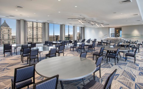 meeting room with round tables and blue chairs overlooking tall buildings