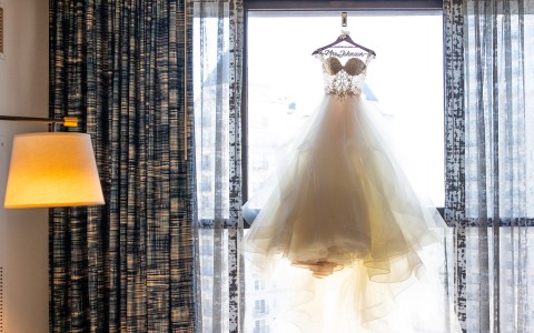 wedding dress hanging up in front of a window
