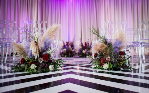 close up shot of black and white chevron floor with flower bouquets behind clear chairs