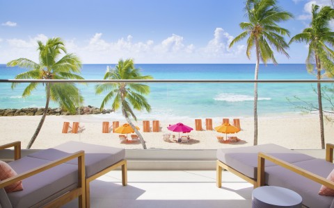 beach view from a balcony with palm trees and beach chairs 