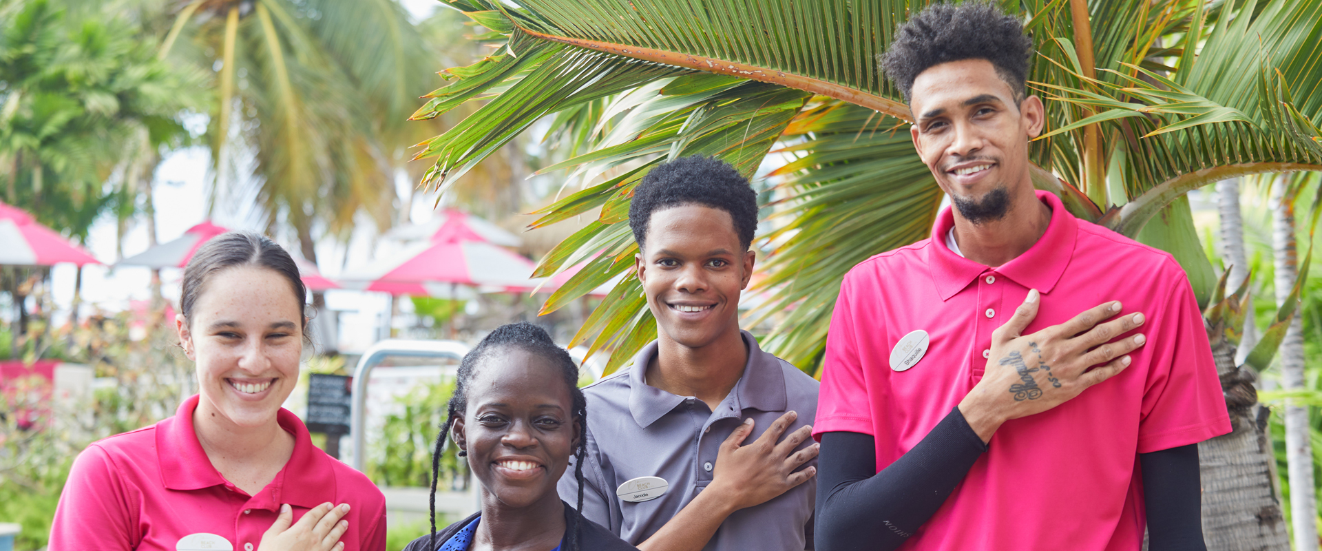 four employees with the right hand on their heart with a palm trees background