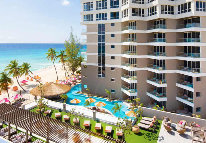 building with a pool and beach view with some pool chairs