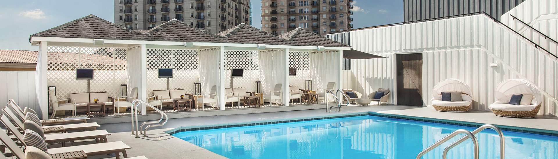 outdoor pool with cabanas, lounge chairs, and suntents