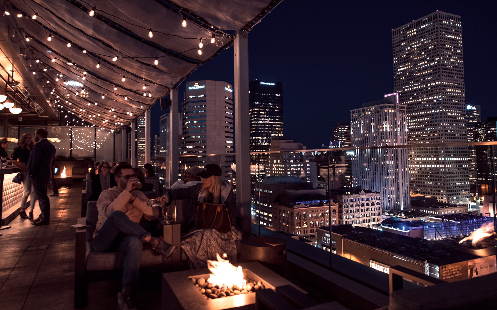 people gathered at the rooftop bar having some fun and warm time up at night