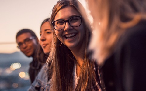 people gathered sitting at the rooftop bar and a lady smiling looking at someone