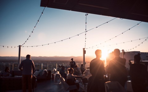 people gathered at a rooftop bar at sunset