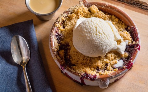 blueberry crumble in a pot with ice cream on top of it