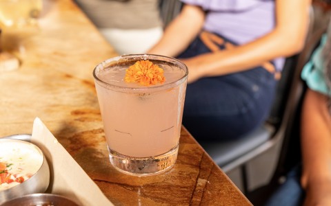 pink cocktail with an orange flower on top