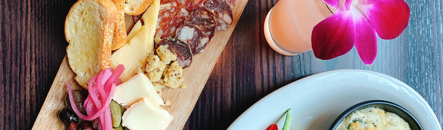 charcuterie board with flower in a drink next to it