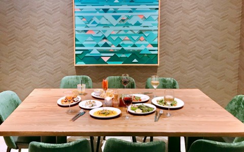 big square table with different dishes and drinks served and green arm chairs