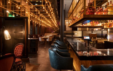 a room with a bar chairs and tables