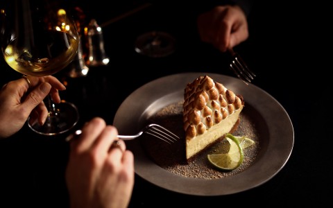 a pie on a plate and two people holding a fork