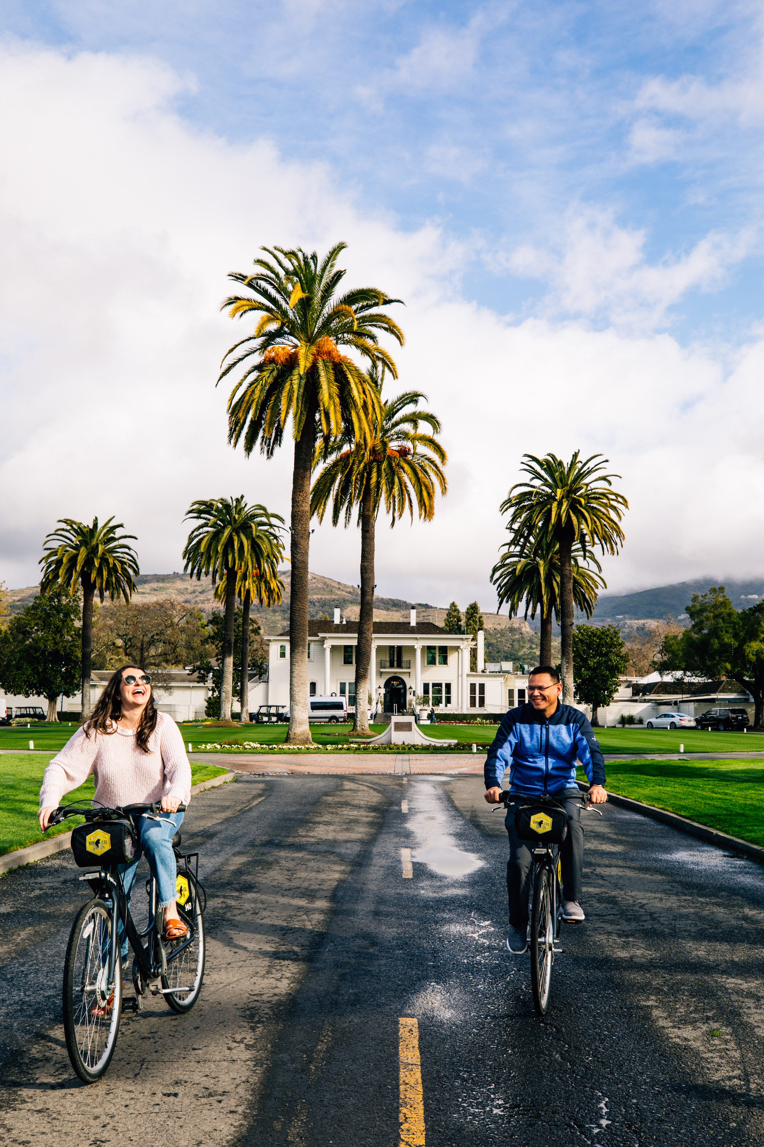man and woman riding bikes next to each other and laughing 