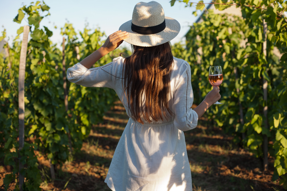 brunette in vineyard holding wine glass