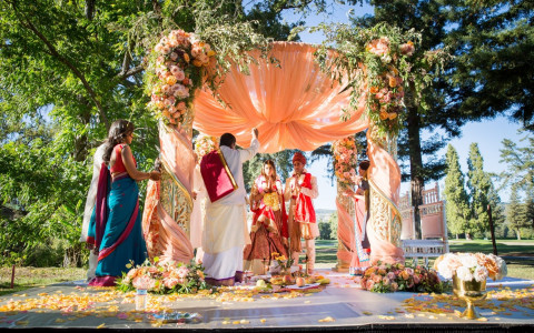 Wide shot of an Indian Wedding Ceremony with a colorful arch and beautiful flowers for decor
