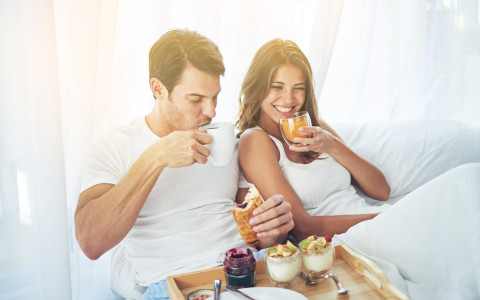 Man and woman eating breakfast in bed