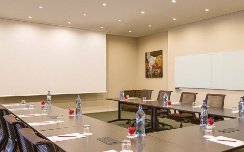 Meeting conference table set up in a u shape and facing a projector screen