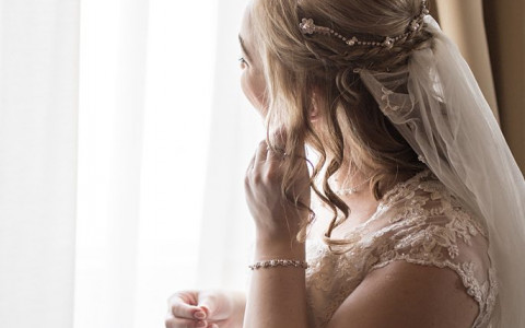 Bride looking out a window putting on earrings
