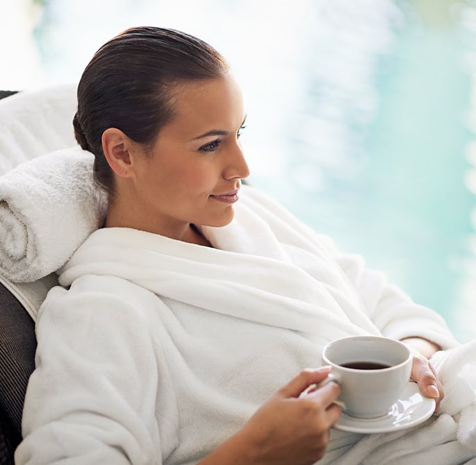 woman drinking a cup of tea by the pool