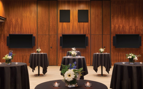 room with cocktail tables with black tablecloth and flowers and candles on top 
