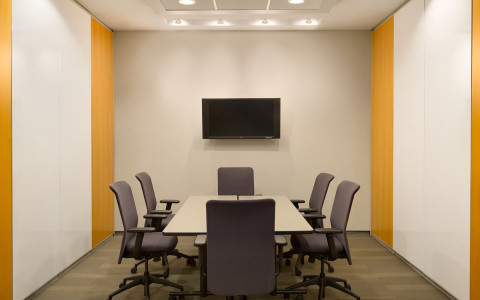 meeting space with a desk and chairs with a tv monitor on the wall 