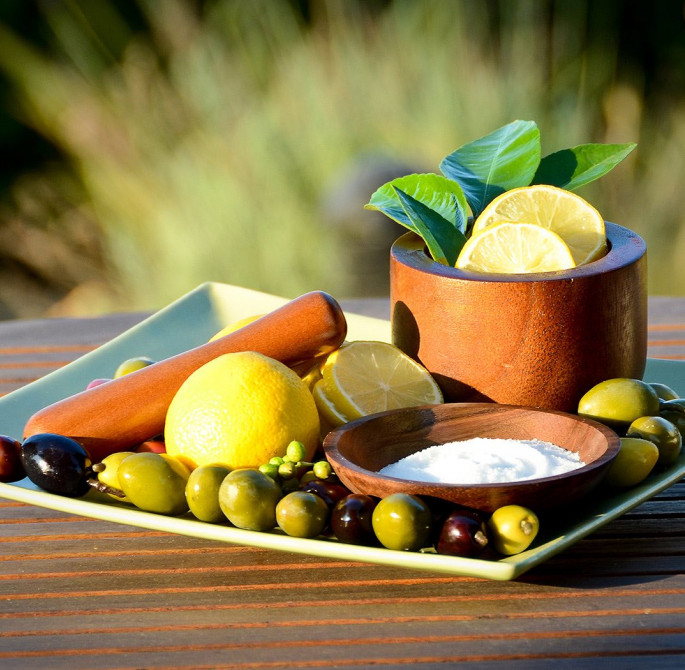 Lemons, lemon slices, olives and wooden bowls arranged on a table