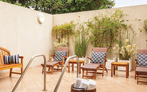 basket of towels next to jacuzzi on a deck with lounge chairs 
