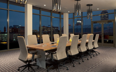 A long wooden conference table is set with tall chairs