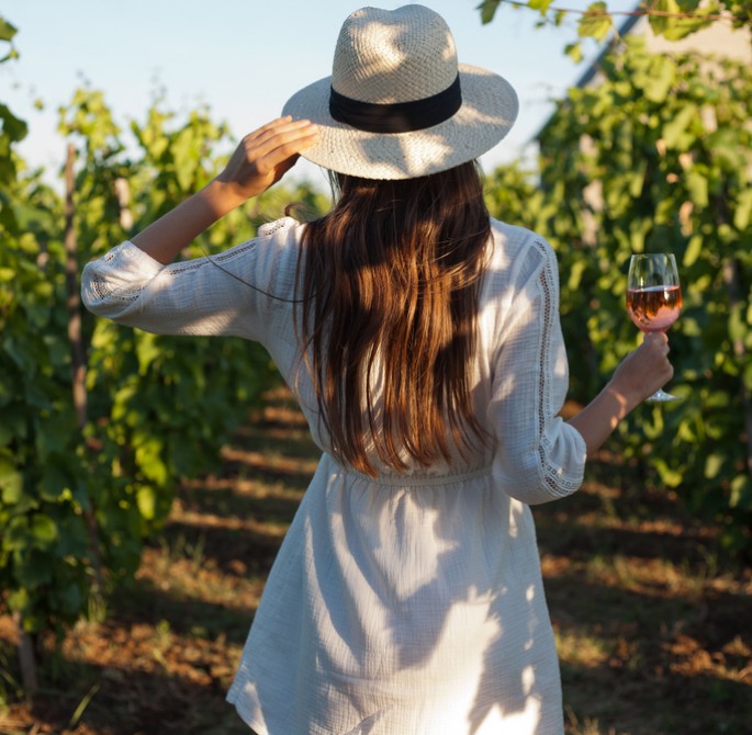 brunette in vineyard holding wine glass