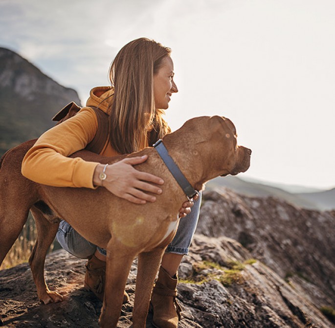 a woman hugging a dog in a hike
