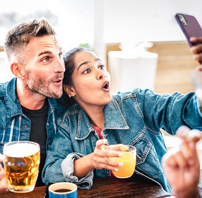 a couple taking a selfie with beers in hand