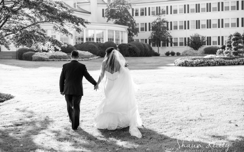 bride and groom holding hands on the front lawn of Seaview, a Dolce Hotel