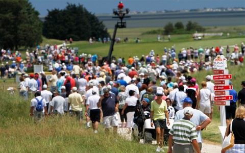 a group of people moving around on a golf course during a tournament