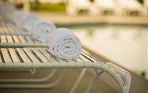 pool towels rolled up on pool chairs by a pool