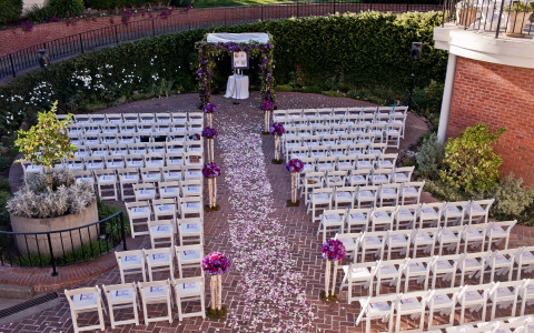 Arbor pre-ceremony setup with white chairs and beautiful purple and white rose pedals