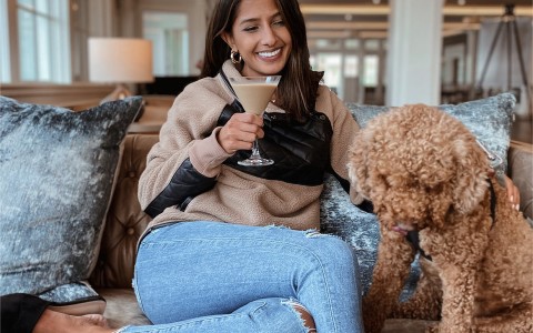 girl drinking a cocktail with a dog next to her