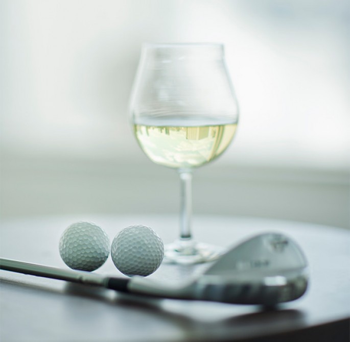 glass of white wine and golf balls