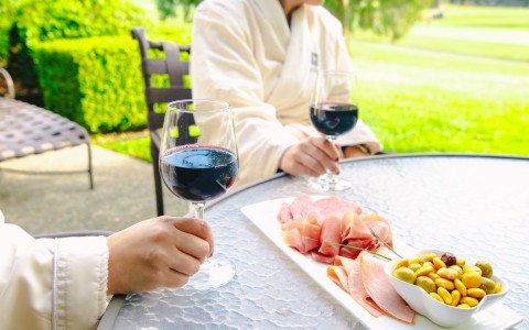 Resort guests sipping red wine with charcuterie out on their resort patio